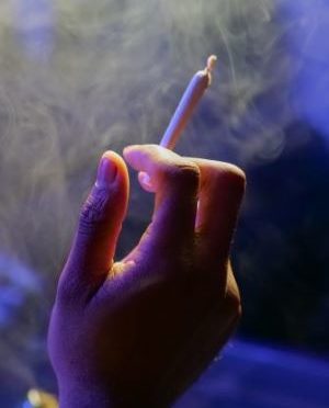 A hand holding up a lit joint